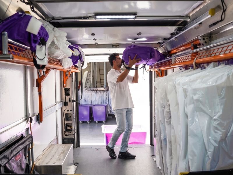 A PurpleTie driver loading garments into a delivery van